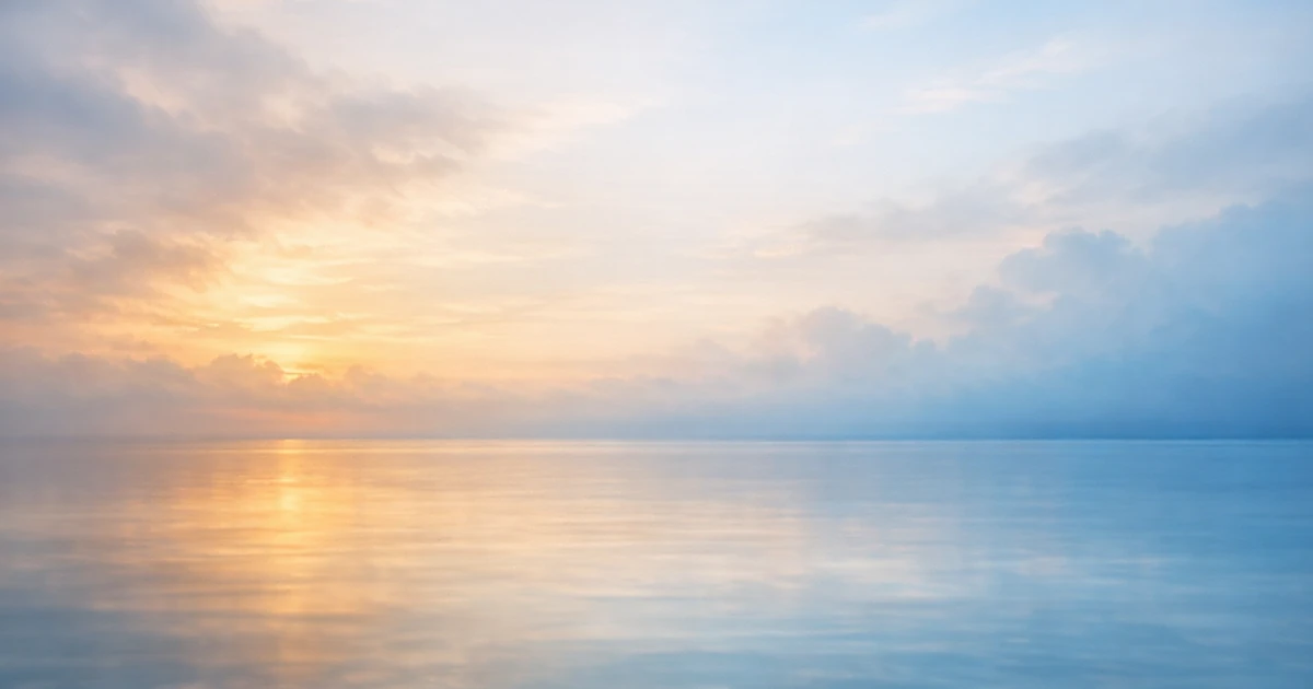 Abstract peaceful scene with soft light filtering through clouds over calm water in warm and cool tones